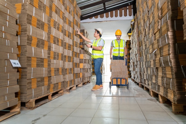 Trabajo en equipo de trabajadores en almacén preparando cajas de cartón de mercancías en un palet en almacén para su envío.