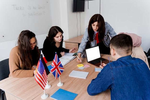 Trabajo en equipo. Trabajando en grupo multiétnico de estudiantes. El profesor estudia idiomas extranjeros juntos en clase.