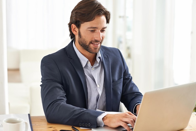 El trabajo es una brisa hoy. Un apuesto hombre de negocios que trabaja en su computadora portátil.