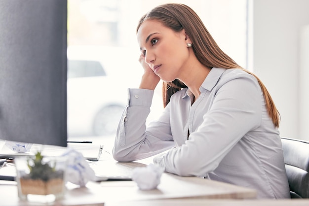 Este trabajo es tan aburrido Fotografía de una atractiva joven empresaria sentada sola en la oficina y sintiéndose aburrida mientras usa su computadora