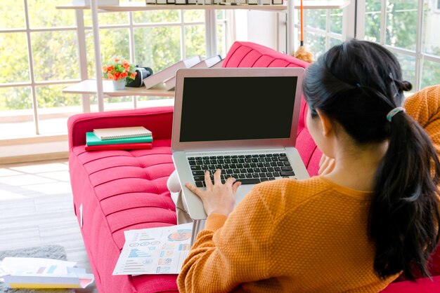 Trabajo femenino con portátil en el sofá en casa