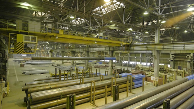 Foto trabajo de grúa interior amarilla colgada de una grúa en la planta para la producción de tuberías