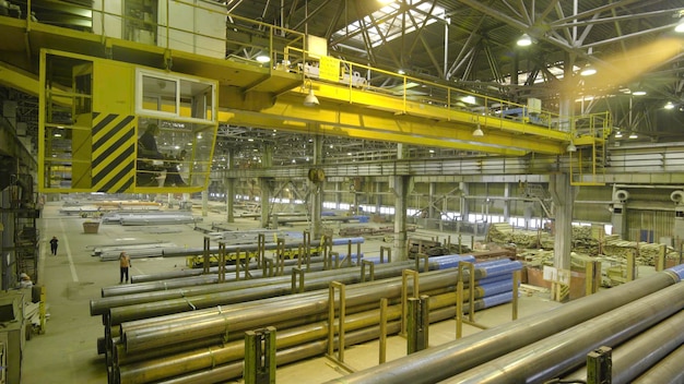 Trabajo de grúa interior amarilla colgando de una grúa en la planta para la producción de tuberías