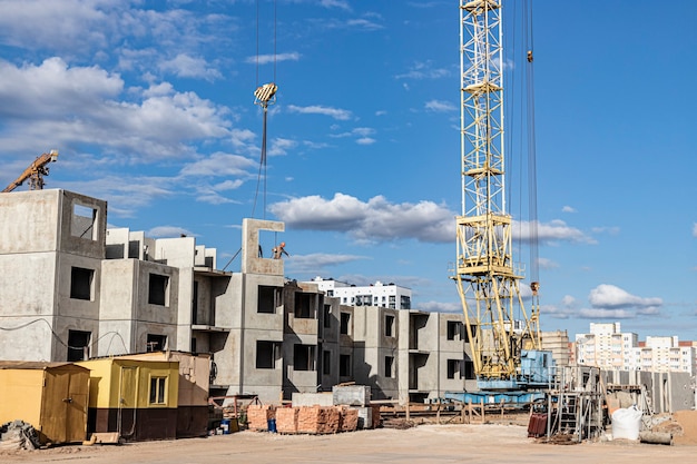 El trabajo de las grúas torre contra el fondo del cielo del atardecer. Construcción de viviendas modernas. Ingeniería Industrial. Construcción de vivienda hipotecaria.