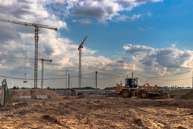 El trabajo de las grúas torre contra el fondo del cielo del atardecer. Construcción de viviendas modernas. Ingeniería Industrial. Construcción de vivienda hipotecaria.