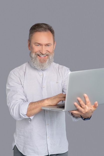 En el trabajo. Hombre barbudo que trabaja con su gadget