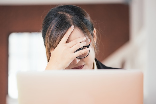 Trabajo independiente de la tensión de la sensación de la mujer del negocio joven asiático que trabaja con la computadora portátil.