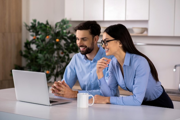 Trabajo inspirador Jóvenes colegas de negocios positivos que usan su computadora portátil mientras trabajan en el proyecto