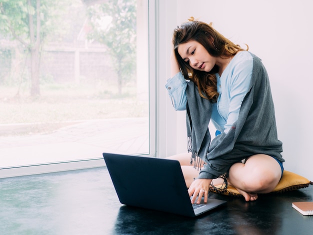 El trabajo en línea bastante asiático de Internet de la mujer en casa y relaja forma de vida con su labtop