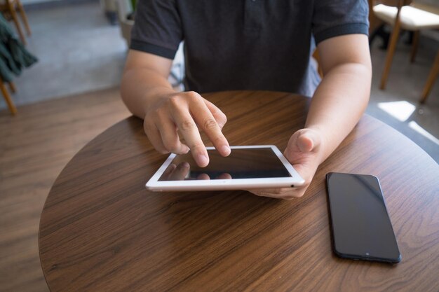 Trabajo en línea desde el concepto de oficina portátil en casa Vista superior de la mano del joven que trabaja en la tableta