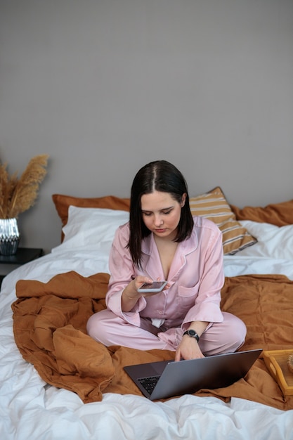 Foto trabajo en línea a distancia. mujer feliz que trabaja en la oficina de trabajo de forma remota desde su casa en la cama. usar la computadora y tomar café.