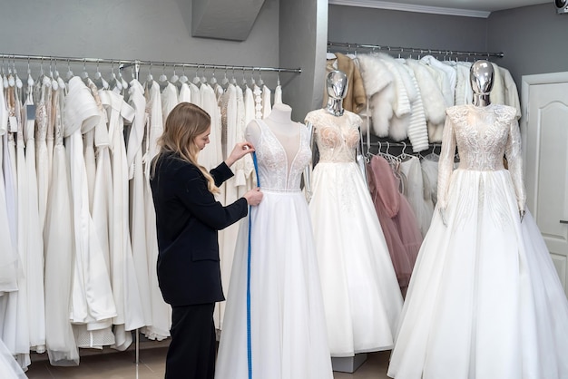 Trabajo de modista en el salón de bodas con cinta métrica centimétrica vestido elegante blanco