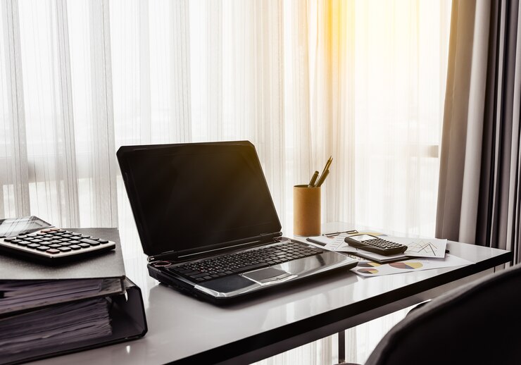 Trabajo de oficina con la computadora portátil en la mesa blanca, ventanas laterales en la oficina