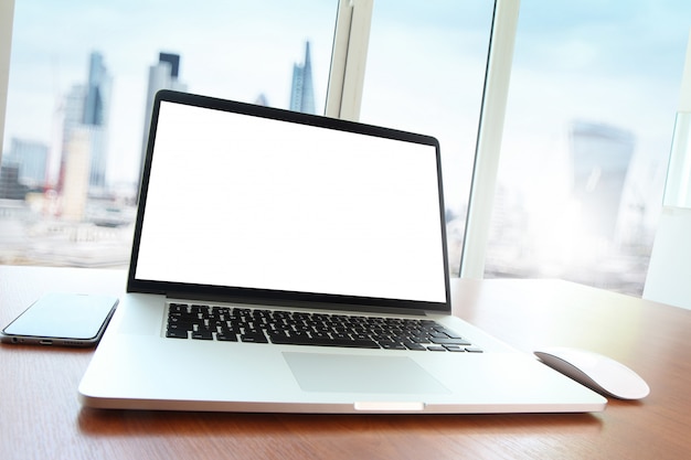 Trabajo de oficina con computadora portátil con pantalla en blanco y teléfono inteligente en mesa de madera