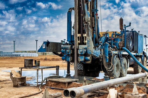 Trabajo de una plataforma de perforación en un sitio de construcción sobre un fondo de cielo azul. Exploración de minerales útiles. Industria y construcción.