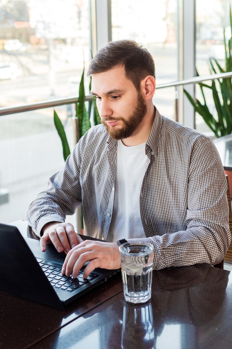 Foto trabajo remoto. hombre de negocios usando laptop, hombre caucásico sentado a la mesa en la cafetería, trabajando en la computadora portátil, bebe agua