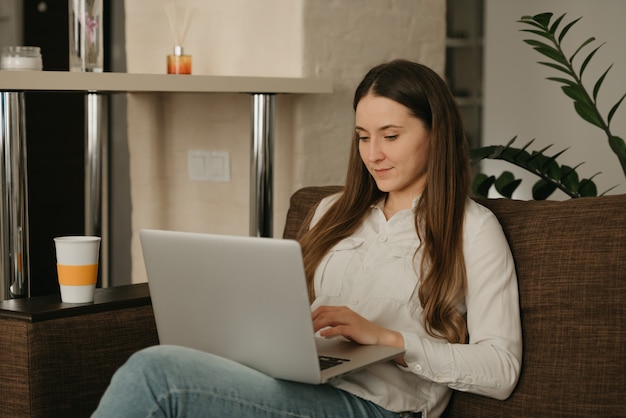 Trabajo remoto. Una mujer joven caucásica que trabaja remotamente en su computadora portátil.