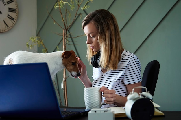 Trabajo remoto desde la oficina en casa mujer en el lugar de trabajo con su perro mujer independiente usando una computadora portátil en la vida