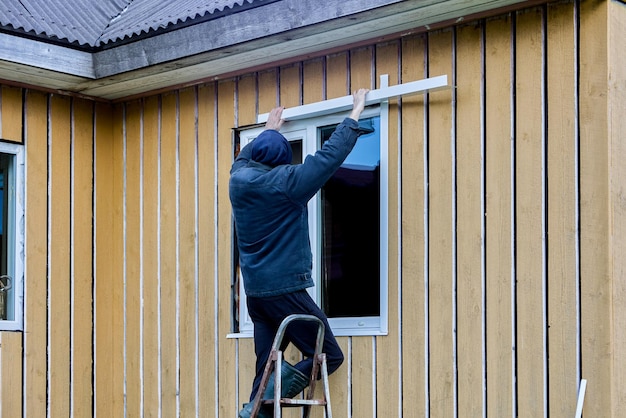 Trabajos de acabado exterior en el marco y la casa de paneles en el lado de la fachada el techador instala jambas de apertura de ventanas