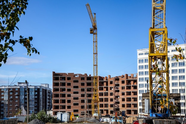 Trabajos en curso en un nuevo bloque de apartamentos Edificio alto en construcción con grúas Lugar de construcción de nuevo edificio