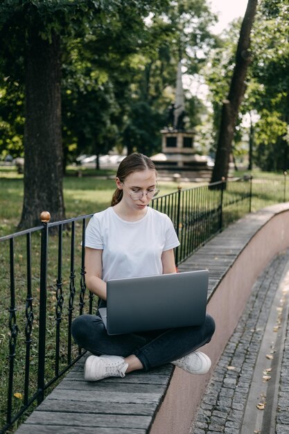 Trabajos en línea para estudiantes universitarios joven estudiante buscando trabajo con portátil al aire libre