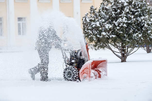 Trabajos de remoción de nieve con quitanieves. Hombre quitando nieve. fuertes precipitaciones y montones de nieve