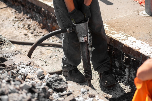 Trabajos de reparación en la calle de la ciudad. Los trabajadores profesionales desmontan parte del camino con una herramienta profesional. Los trabajadores quitan el asfalto y cavan un hoyo. Expertos técnicos, flujo de trabajo en la calle de la ciudad.