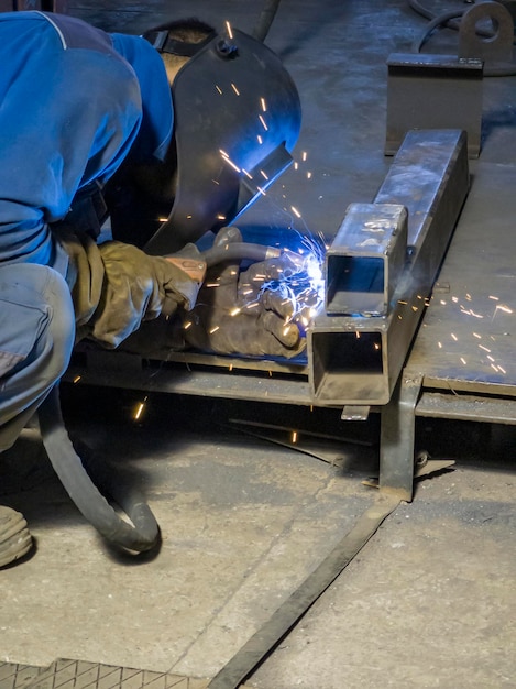 Trabajos de soldadura con equipos para chispas de hierro metálico de acero en la fábrica de la industria pesada de fabricación en interiores