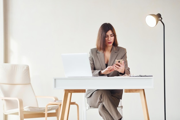 Trabalha no escritório por laptop Jovem em roupas formais está dentro de casa Concepção de estilo