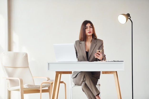 Trabalha no escritório por laptop Jovem em roupas formais está dentro de casa Concepção de estilo