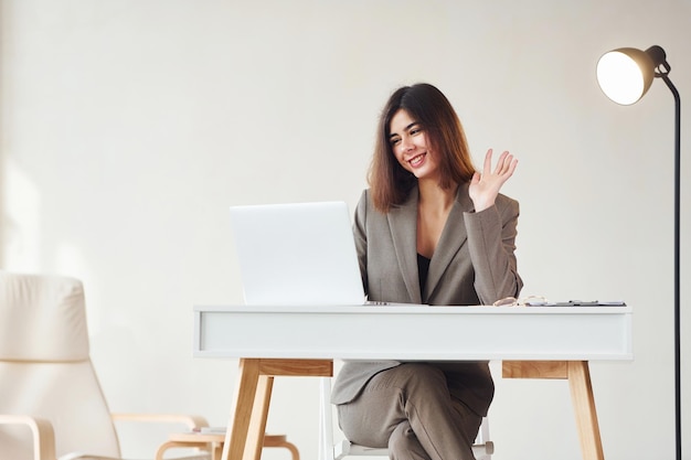 Trabalha no escritório por laptop Jovem em roupas formais está dentro de casa Concepção de estilo