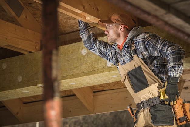 Trabalhador caucasiano verifica a estrutura de madeira do novo sótão