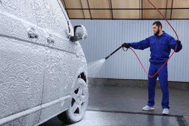 Trabalhador cobrindo automóvel com espuma na lavagem de carros