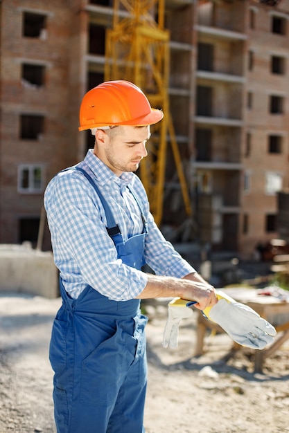 Trabalhador com capacete laranja em um canteiro de obras usando luvas