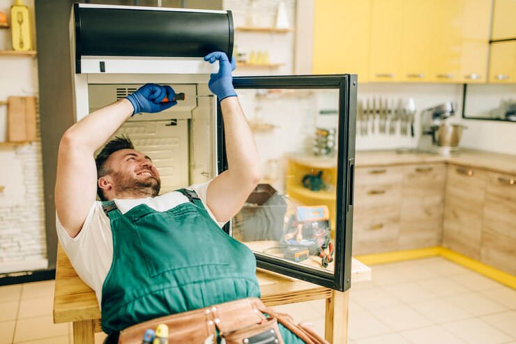 Foto trabalhador com luvas conserta geladeira em casa
