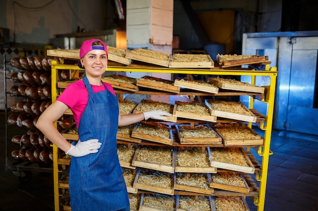 Foto trabalhador com uma caixa de macarrão. a menina trabalha na produção de espaguete. fazendo macarrão. fábrica de massas.