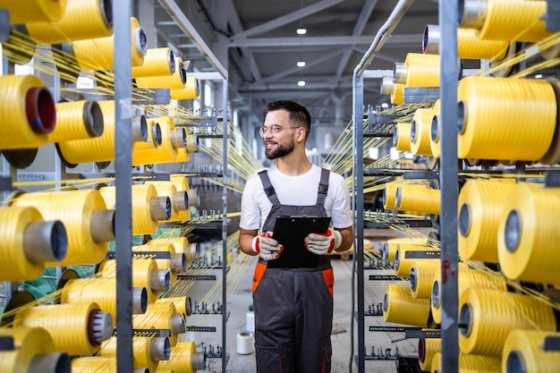 Trabalhador com uma lista de verificação que controla a produção na máquina de tricotar dentro de uma fábrica têxtil