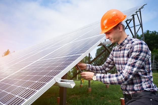 Trabalhador conecta painéis solares em uma plantação verde Construção de casa