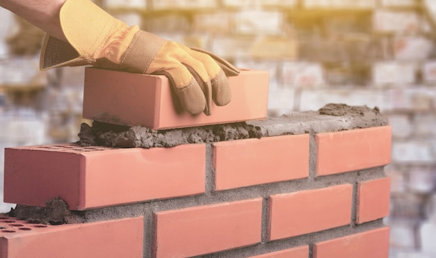 Foto trabalhador constrói uma parede de tijolos na casa