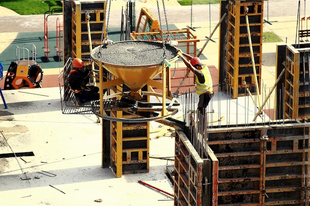 Trabalhador construtor com tubo de bomba de concreto montada em caminhão derramando cimento em reforço de cofragem