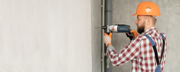 trabalhador construtor trabalhando perforador com grande broca longa perfurado parede de concreto em fundo branco Serviço de reparação e conceito de construção Banner