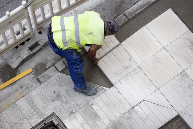 Trabalhador da construção civil colocando uma telha consertando uma calçada. conceito de manutenção