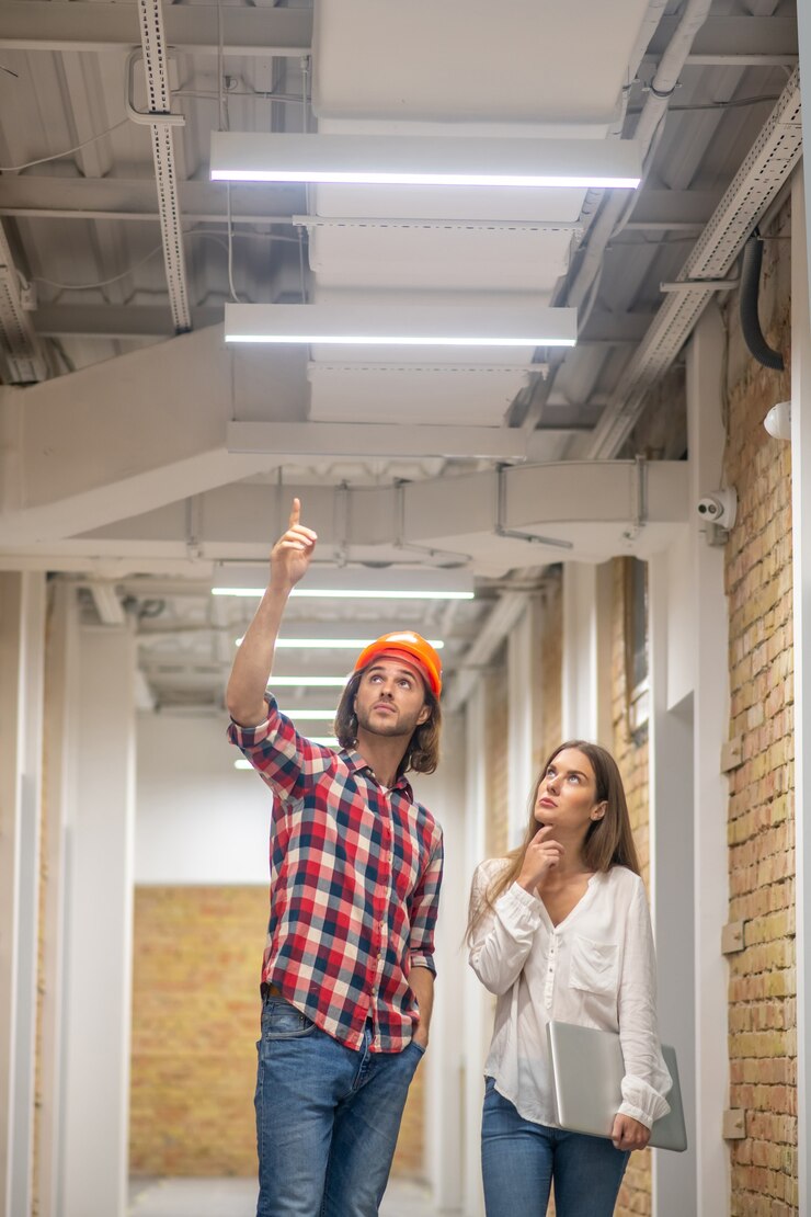 Foto trabalhador da construção civil com capacete laranja falando com uma cliente