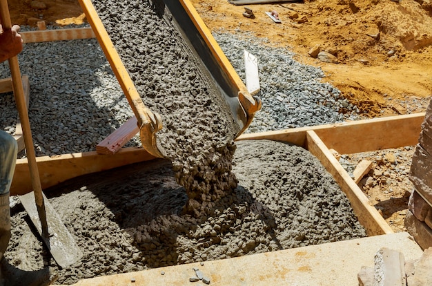 Trabalhador da construção civil despeje cimento para calçada em obras de concreto com caminhão betoneira com carrinho de mão