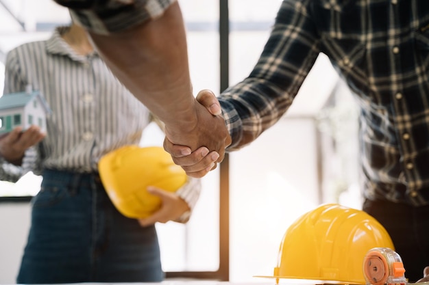 Foto trabalhador da construção civil e empreiteiro cliente apertando as mãos com o construtor de equipe no escritório pela manhã