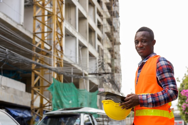 Trabalhador da construção civil jovem africano segurando uma prancheta