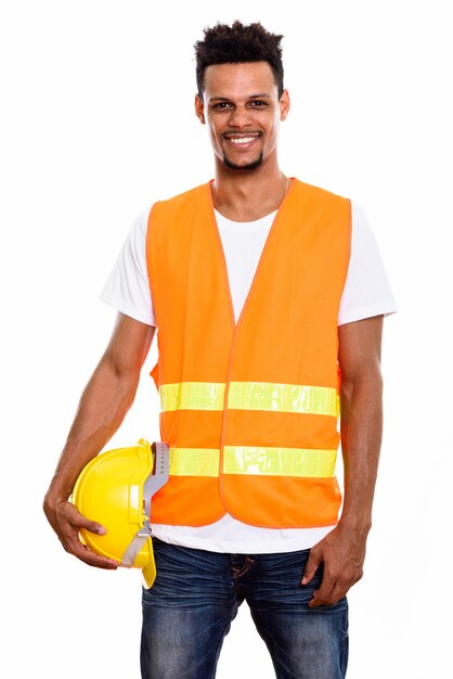 Trabalhador da construção civil jovem feliz africano sorrindo enquanto segura um capacete de segurança