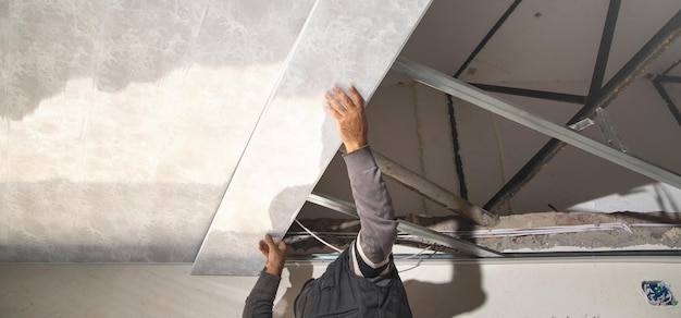 Trabalhador da construção civil monta um teto suspenso