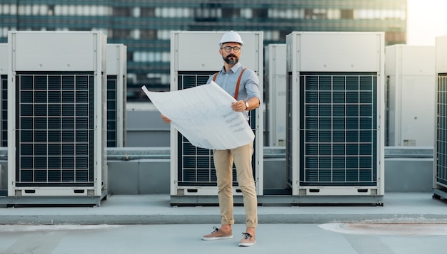 Trabalhador da construção civil profissional no canteiro de obras. Técnico de engenharia elétrica no telhado do prédio.