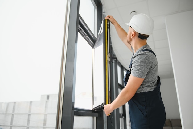 Trabalhador da construção civil reparando janela de plástico com chave de fenda dentro de espaço para design de banner de texto